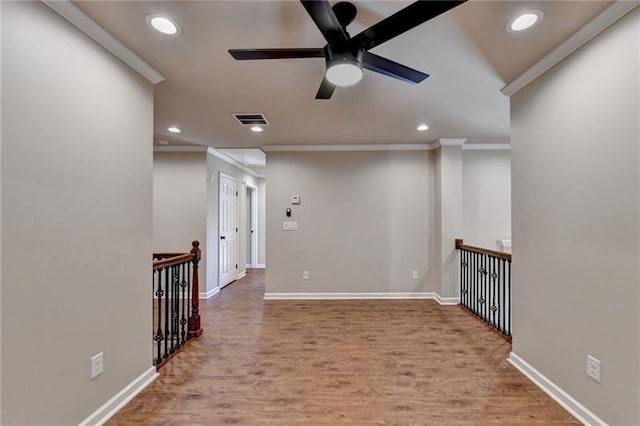 empty room featuring recessed lighting, wood finished floors, visible vents, and crown molding