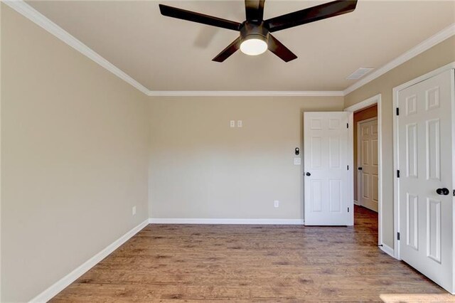 empty room featuring crown molding, ceiling fan, light wood-style flooring, and baseboards