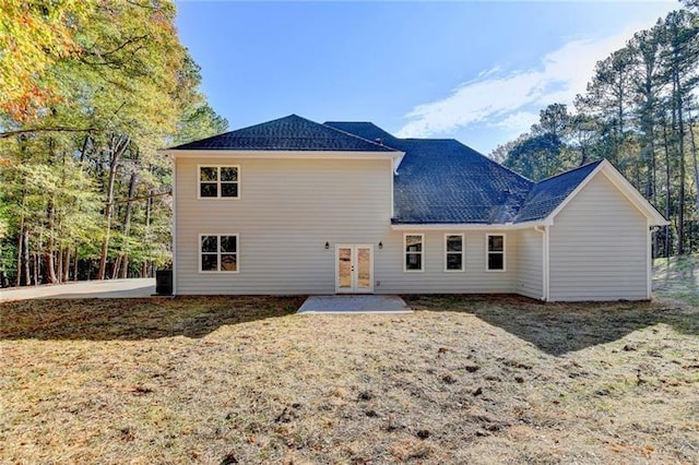 rear view of house with a yard, french doors, and a shingled roof