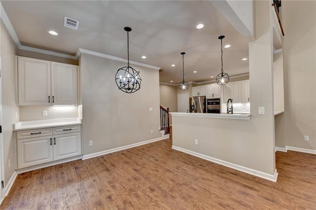 kitchen featuring visible vents, white cabinetry, light countertops, appliances with stainless steel finishes, and decorative light fixtures