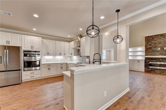 kitchen with a peninsula, white cabinetry, light countertops, appliances with stainless steel finishes, and hanging light fixtures