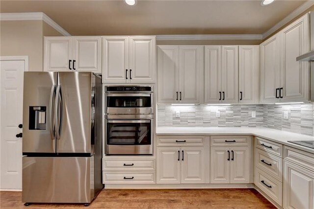 kitchen featuring light countertops, decorative backsplash, appliances with stainless steel finishes, light wood-style floors, and white cabinets