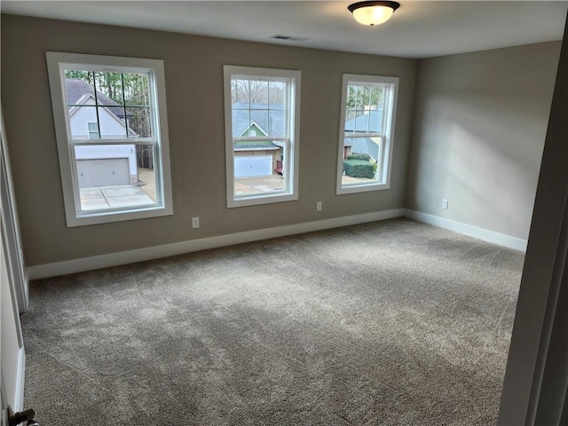 carpeted empty room featuring plenty of natural light, visible vents, and baseboards