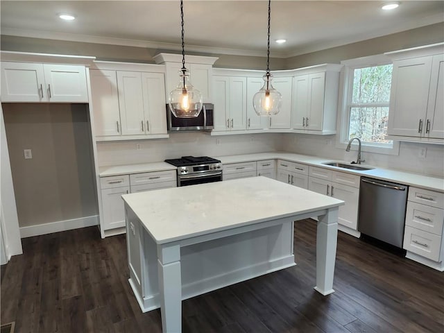 kitchen featuring appliances with stainless steel finishes, decorative light fixtures, light countertops, white cabinetry, and a sink