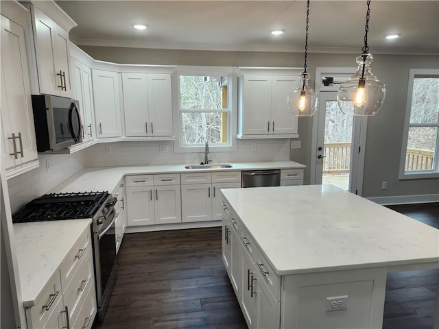 kitchen with appliances with stainless steel finishes, white cabinetry, a sink, and crown molding