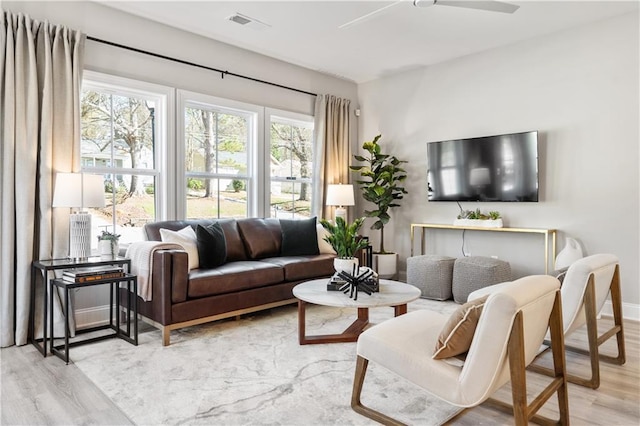 living room featuring light wood-style floors, baseboards, visible vents, and a ceiling fan