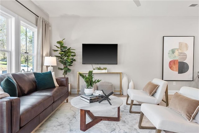 living room with light wood-type flooring, visible vents, and baseboards