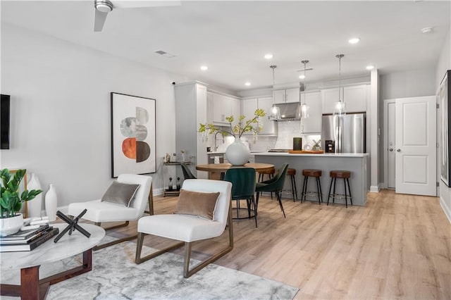 living room with baseboards, visible vents, a ceiling fan, light wood-type flooring, and recessed lighting