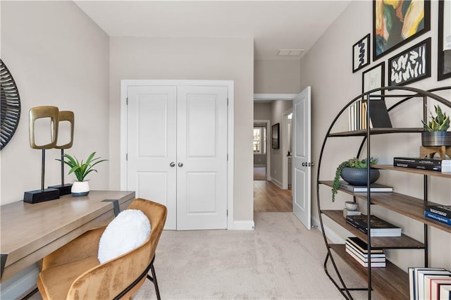 office area featuring baseboards, visible vents, and light colored carpet