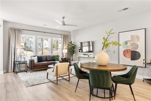 dining room with light wood finished floors, ceiling fan, visible vents, and baseboards