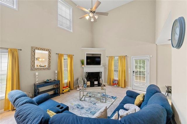 carpeted living room featuring visible vents, baseboards, a fireplace with raised hearth, a ceiling fan, and a high ceiling