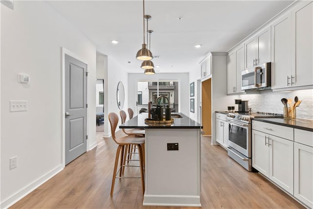 kitchen with a breakfast bar area, dark countertops, tasteful backsplash, a sink, and stainless steel appliances