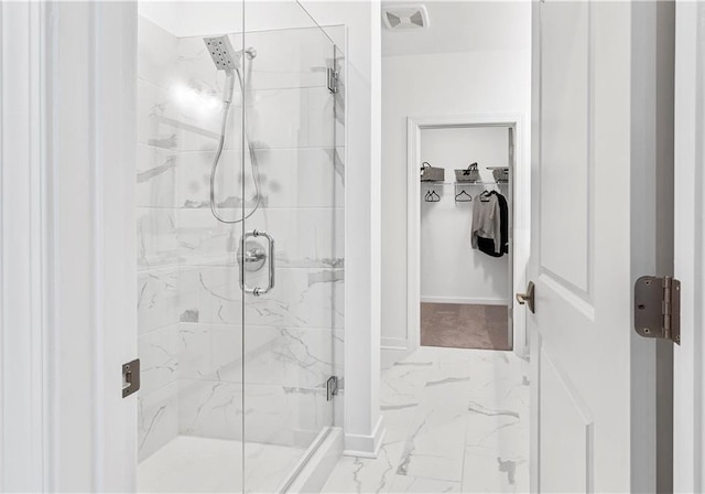 bathroom featuring a walk in closet, marble finish floor, baseboards, visible vents, and a stall shower