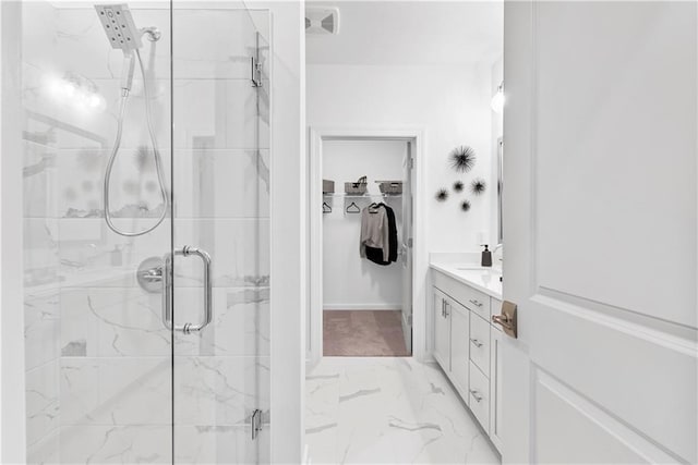 bathroom with a walk in closet, a marble finish shower, marble finish floor, and vanity