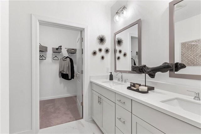 bathroom with double vanity, a sink, marble finish floor, and a spacious closet