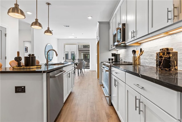 kitchen featuring decorative backsplash, recessed lighting, light wood-type flooring, a sink, and stainless steel appliances