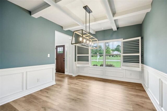 unfurnished dining area with beam ceiling, hardwood / wood-style flooring, and an inviting chandelier