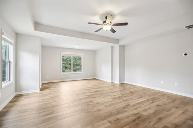 spare room with a raised ceiling, ceiling fan, and light hardwood / wood-style floors