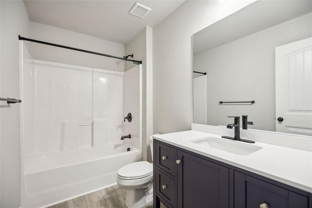 full bathroom with hardwood / wood-style flooring, vanity,  shower combination, and toilet