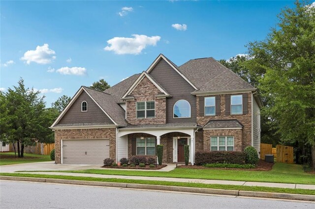 craftsman house featuring a garage, central AC, and a front lawn