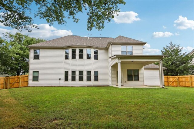 back of house with a patio and a lawn