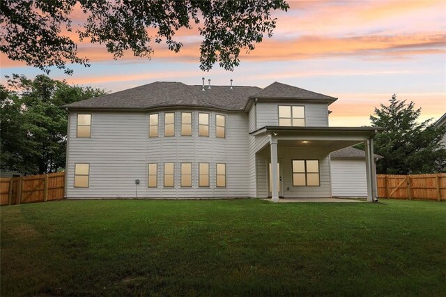 back house at dusk with a yard and a patio area