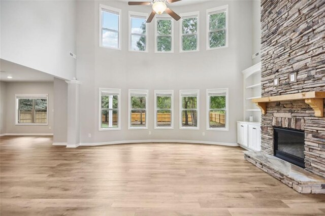 unfurnished living room with plenty of natural light and a stone fireplace