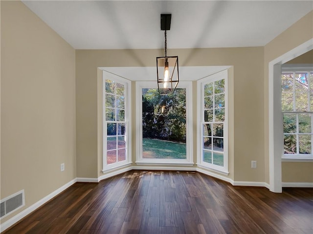 unfurnished dining area featuring a chandelier and dark hardwood / wood-style flooring