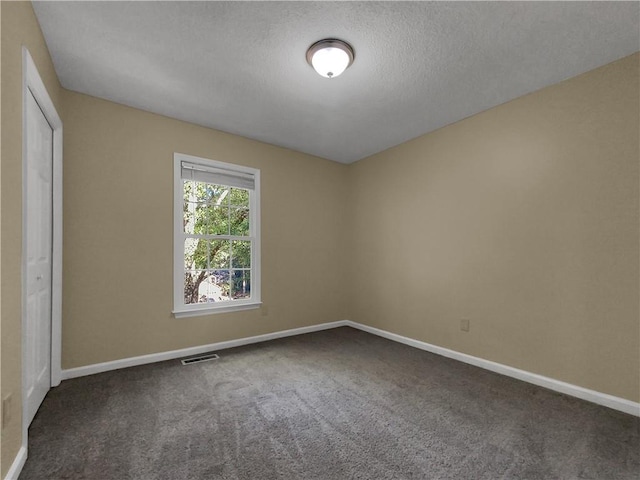 interior space with a textured ceiling and dark carpet