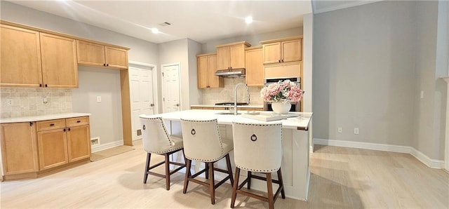 4230 Glen Vista Ct, Duluth, GA 30097 - kitchen with light wood-type flooring, under cabinet range hood, tasteful backsplash, and light countertops