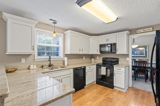 kitchen with black appliances, pendant lighting, white cabinetry, and sink