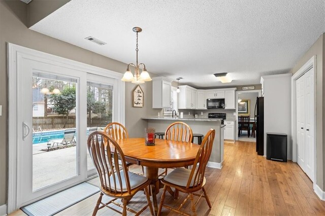 dining area featuring light hardwood / wood-style floors, a textured ceiling, and a chandelier