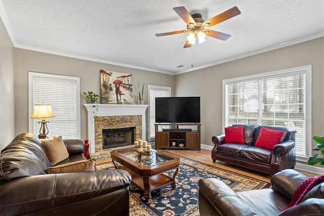 living room with hardwood / wood-style flooring, ceiling fan, a stone fireplace, and a textured ceiling