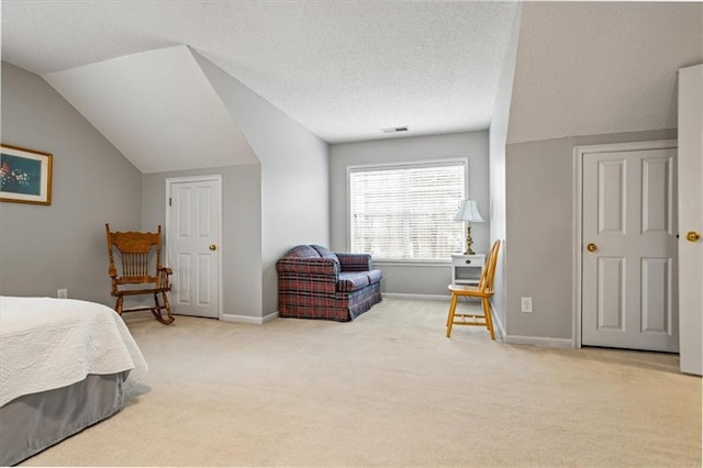 bedroom with a textured ceiling, light colored carpet, and lofted ceiling