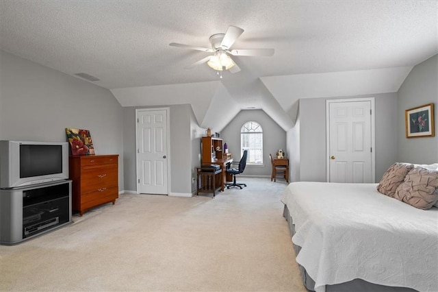 bedroom featuring ceiling fan, light colored carpet, lofted ceiling, and a textured ceiling