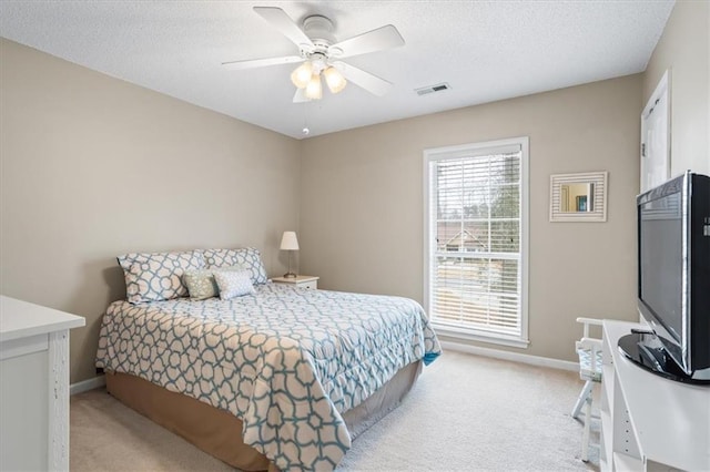 bedroom featuring ceiling fan, light colored carpet, and a textured ceiling