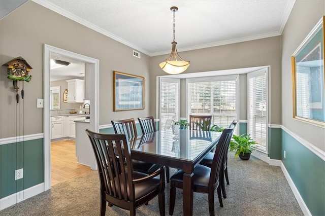 carpeted dining room featuring sink and crown molding