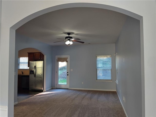 unfurnished room with dark carpet, ceiling fan, and sink