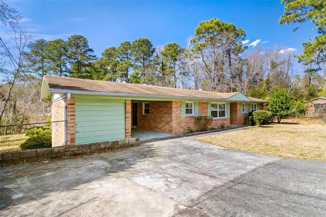 ranch-style home featuring an attached carport, brick siding, fence, concrete driveway, and a front yard