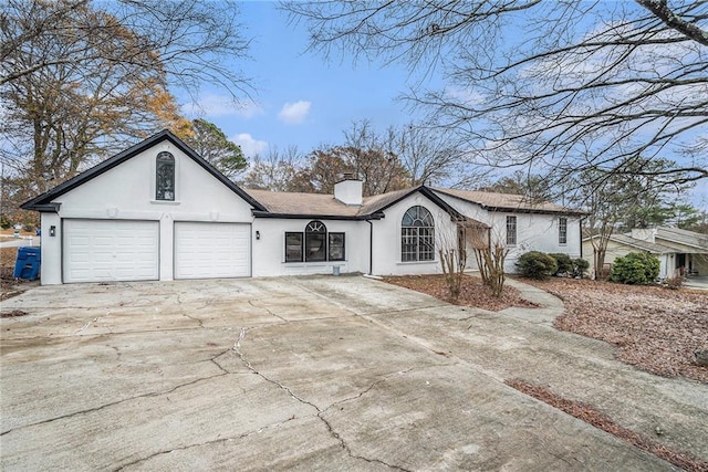 ranch-style home featuring a garage, driveway, a chimney, and stucco siding