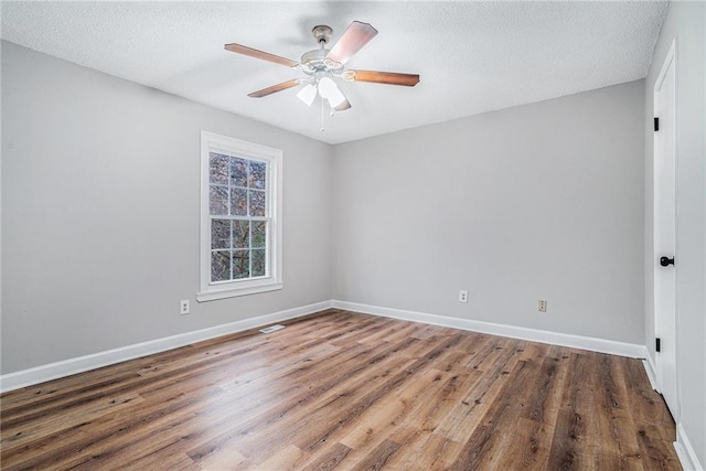 spare room with visible vents, baseboards, ceiling fan, wood finished floors, and a textured ceiling