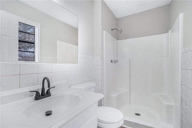 bathroom with a shower, tile walls, toilet, and vanity