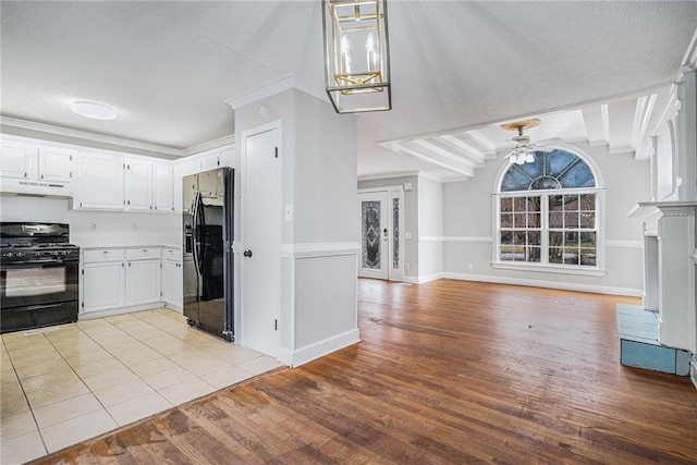 kitchen with open floor plan, under cabinet range hood, light wood-type flooring, black appliances, and white cabinetry