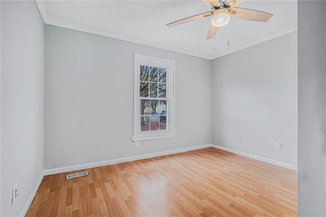 empty room featuring ornamental molding, visible vents, baseboards, and wood finished floors