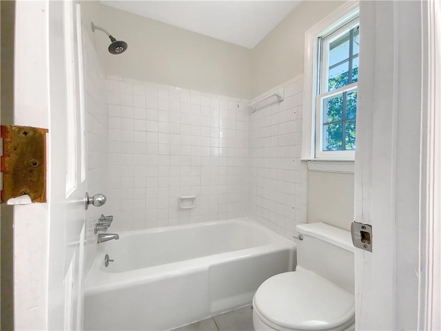 bathroom with tiled shower / bath, toilet, and tile patterned floors