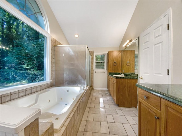 bathroom with vanity, shower with separate bathtub, vaulted ceiling, and tile patterned floors