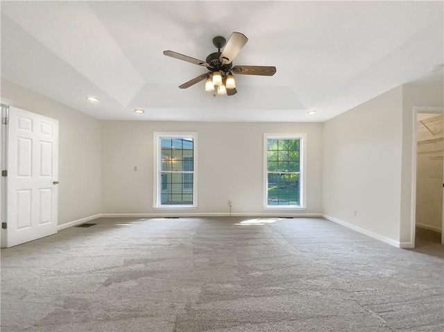 unfurnished room featuring a raised ceiling, carpet flooring, and ceiling fan