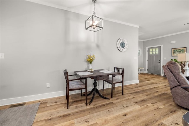 dining room with an inviting chandelier, crown molding, and light hardwood / wood-style floors