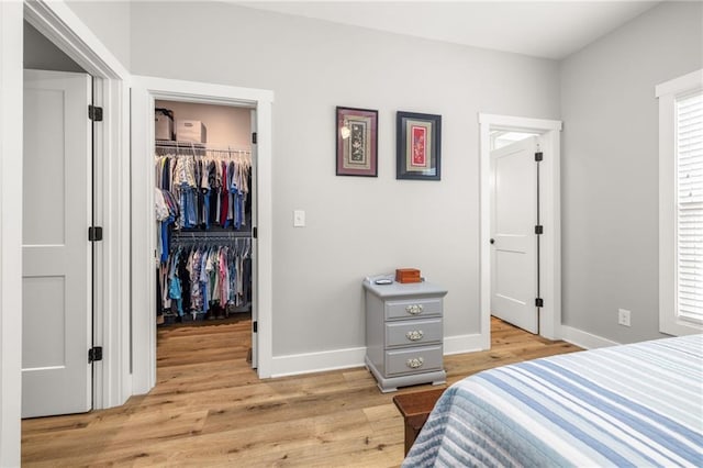 bedroom featuring a spacious closet, a closet, and light wood-type flooring