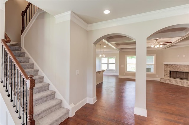 interior space featuring coffered ceiling, crown molding, dark hardwood / wood-style floors, and a brick fireplace